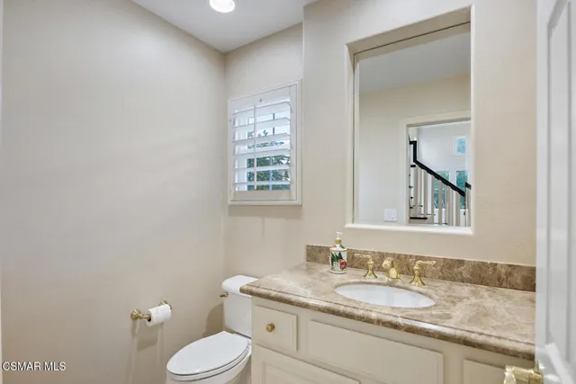 a bathroom with a granite countertop toilet sink and mirror