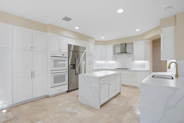 a kitchen with stainless steel appliances granite countertop a refrigerator sink and white cabinets