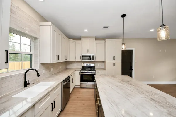 a open kitchen with stainless steel appliances granite countertop a sink a stove and a refrigerator
