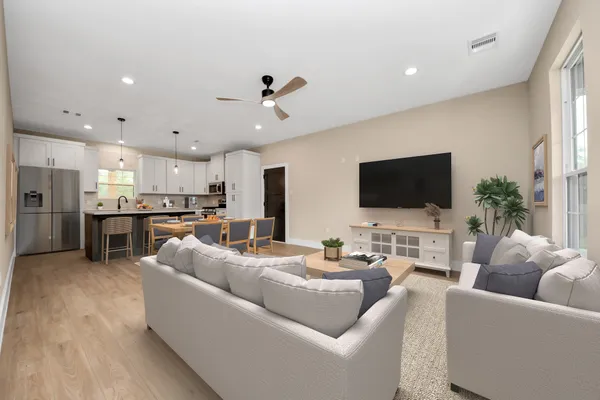 a living room with furniture kitchen view and a flat screen tv