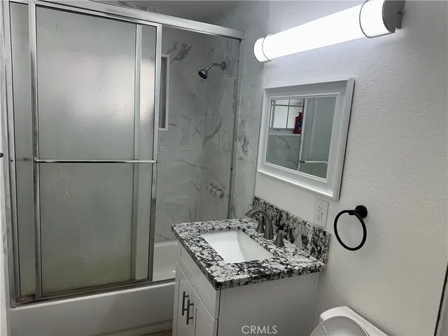 a bathroom with a granite countertop shower sink vanity and mirror