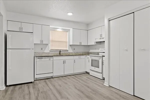 a kitchen with cabinets appliances wooden floor and a window