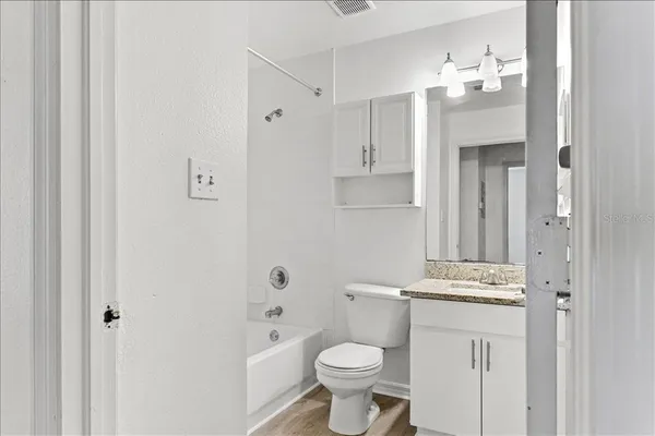 a white bath tub sitting next to a white toilet and vanity
