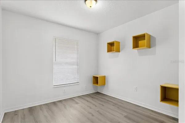 a view of an empty room with wooden floor and a bathroom