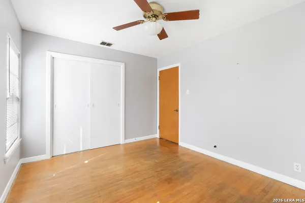 a view of an empty room with a window and wooden floor