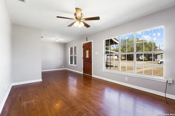 a view of an empty room with a window and wooden floor