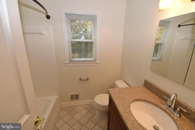 a bathroom with a granite countertop toilet sink and mirror
