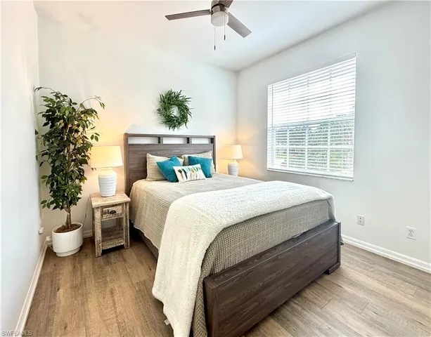 a bed sitting in a bedroom next to a window with a potted plant