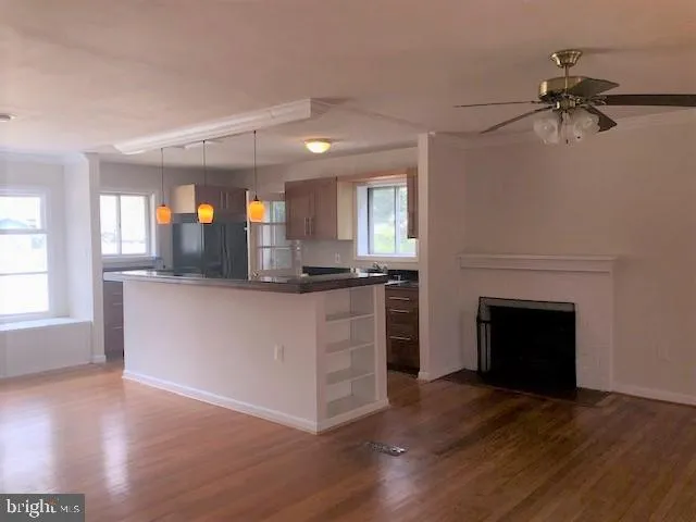 a living room with stainless steel appliances kitchen island a fireplace and wooden floor
