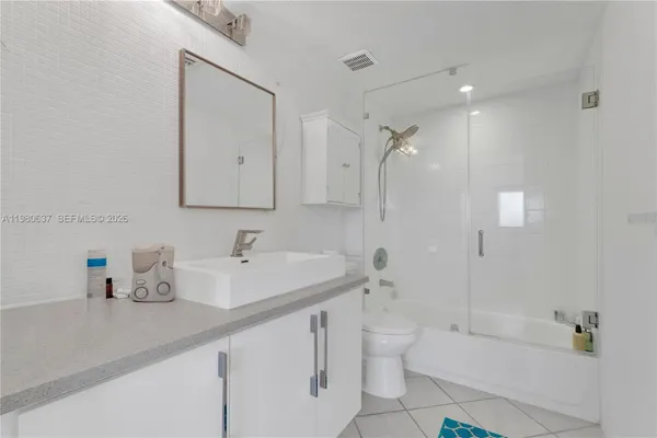 a bathroom with a sink a toilet a mirror and shower