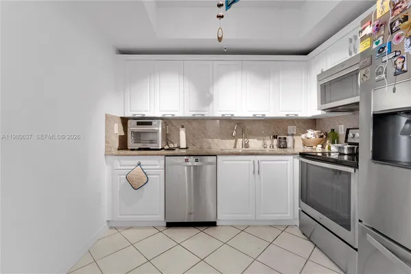 a kitchen with white cabinets a sink and appliances