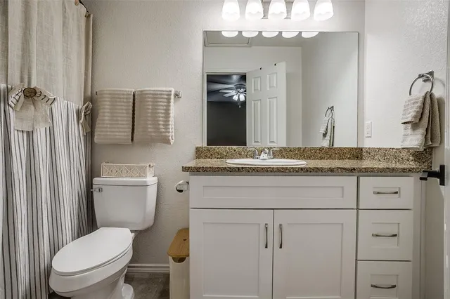 a bathroom with a granite countertop toilet sink and mirror