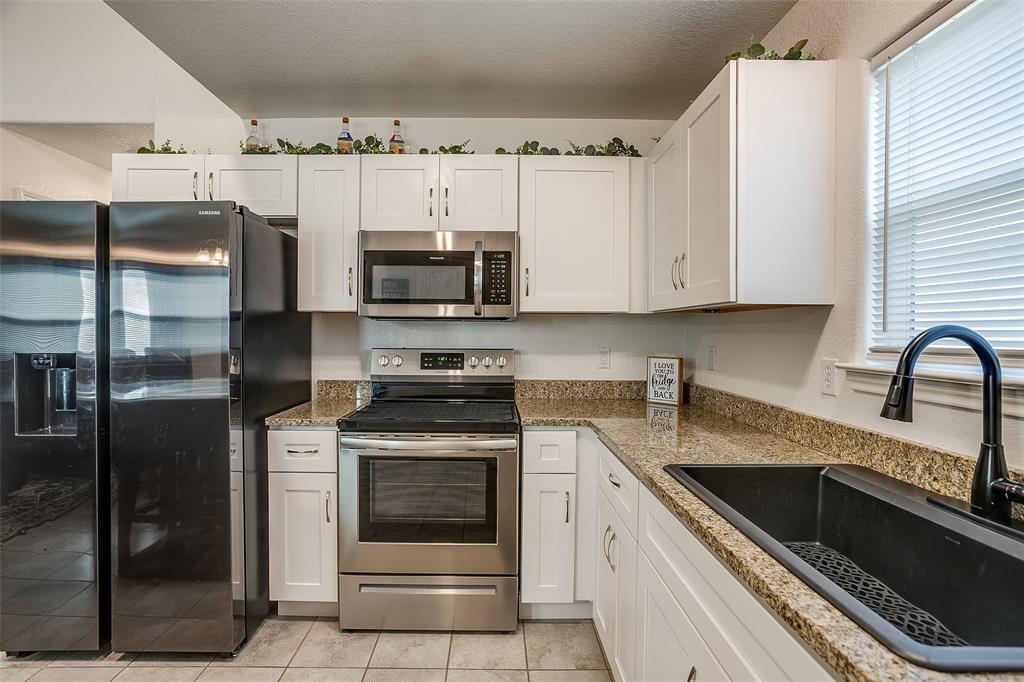 408 South Cleburne Whitney Road Rio Vista, TX 76093 - Photo 6 of 16 a kitchen with stainless steel appliances granite countertop a stove a sink and a microwave