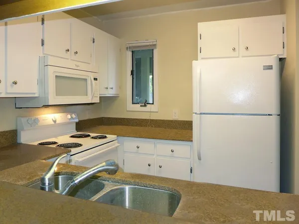 a kitchen with a refrigerator a stove top oven and white cabinets