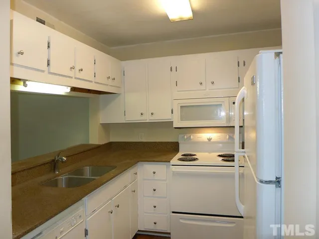a kitchen with granite countertop white cabinets and white appliances