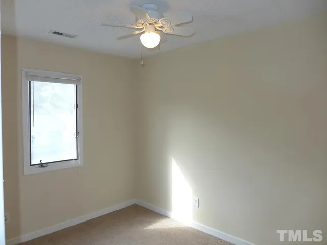 an empty room with a window and a fan