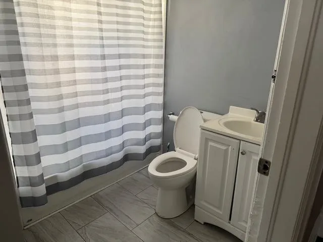 a white toilet sitting next to a shower curtain