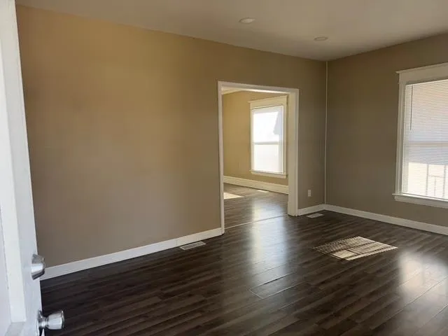 an empty room with wooden floor and windows
