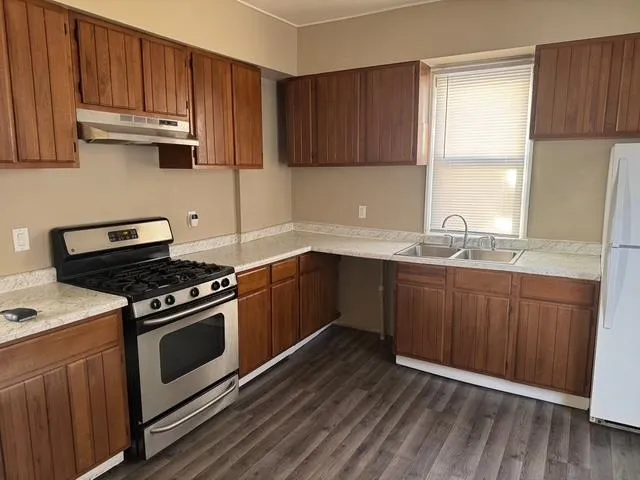 a kitchen with granite countertop wooden cabinets and a stove top oven