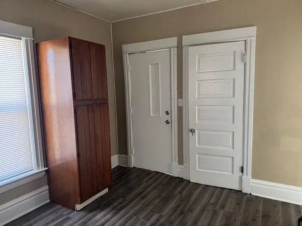 an empty room with wooden floor and closet area