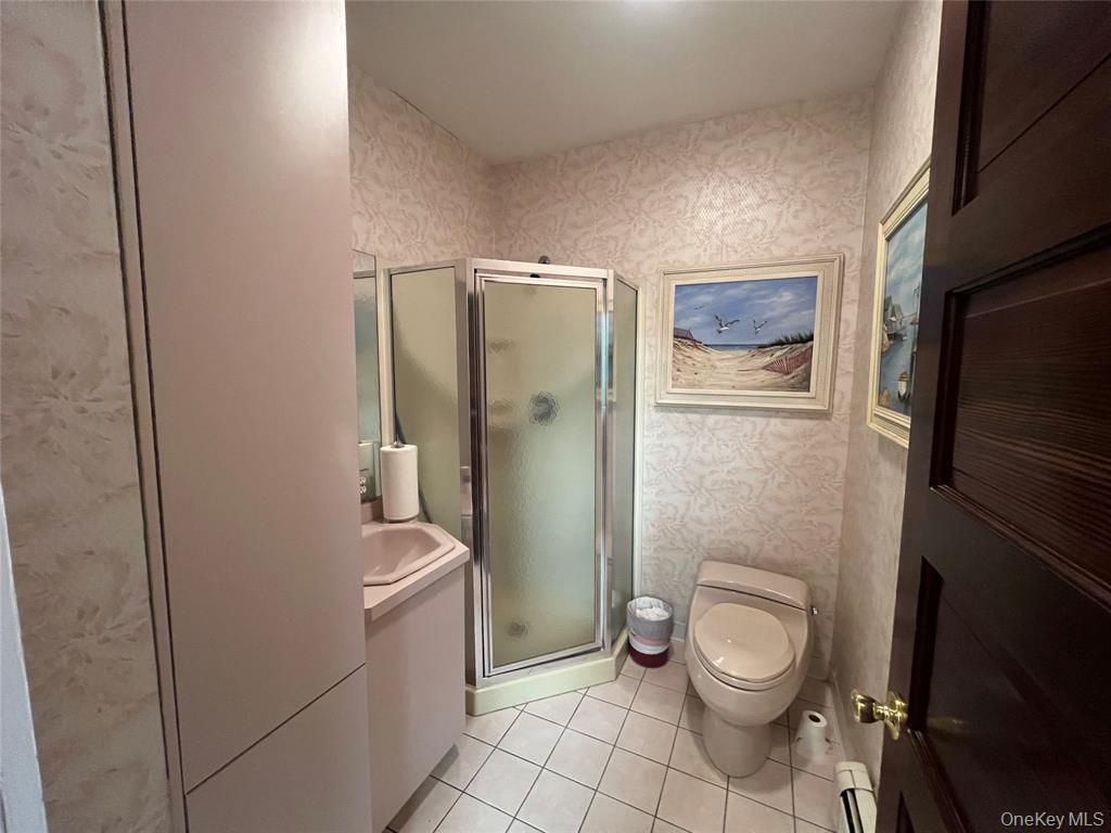 2566 Middle Country Road Centereach, NY 11720 - Photo 17 of 31 a bathroom with a toilet a sink a shower and mirror