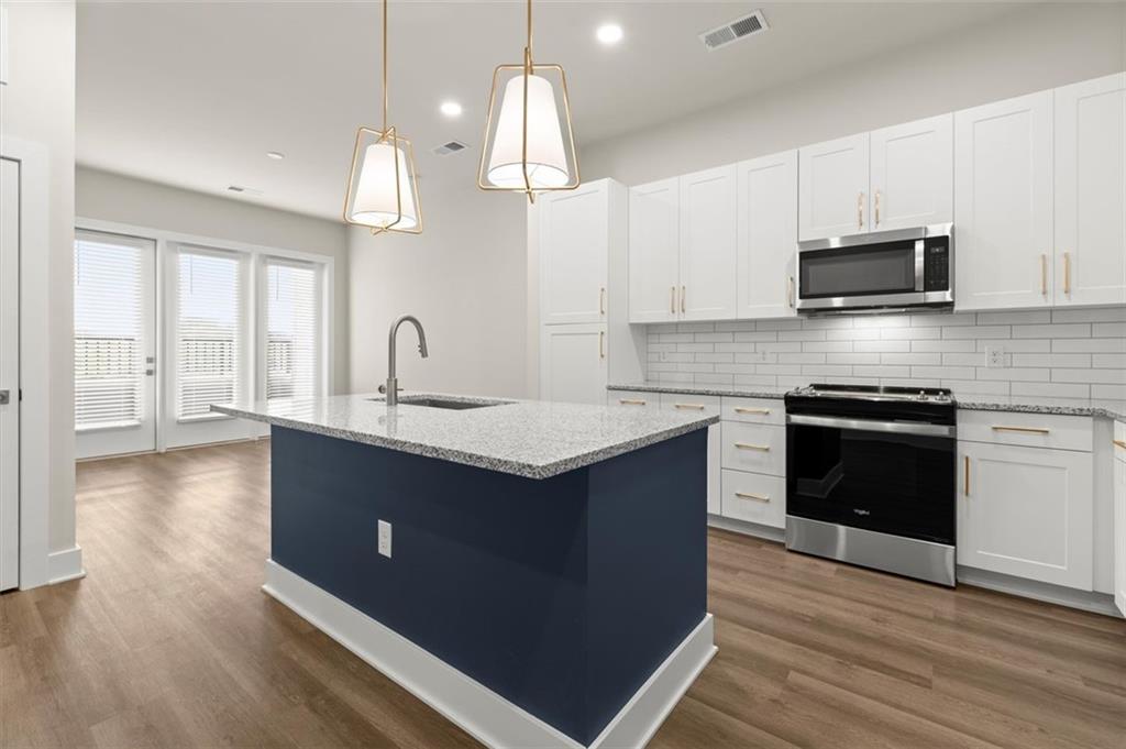 a kitchen with stainless steel appliances granite countertop a sink a stove and a wooden floors