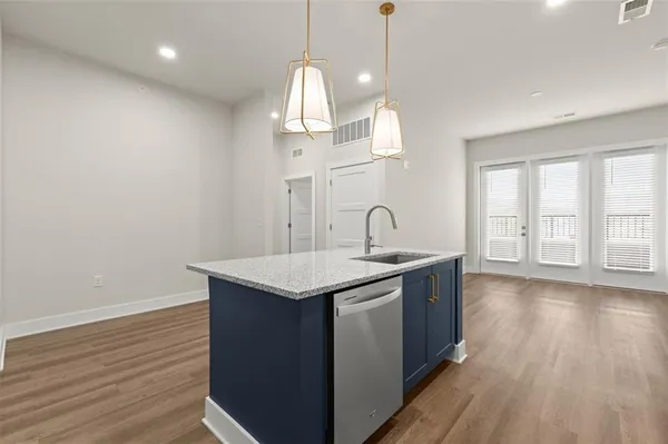 a kitchen with stainless steel appliances granite countertop a sink a stove and a wooden floor