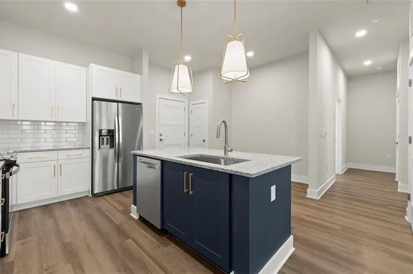a kitchen with a sink a refrigerator and wooden floor