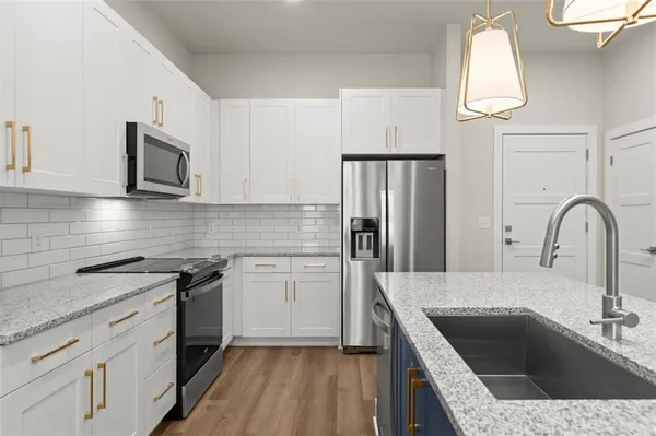 a kitchen with granite countertop a sink stainless steel appliances and cabinets