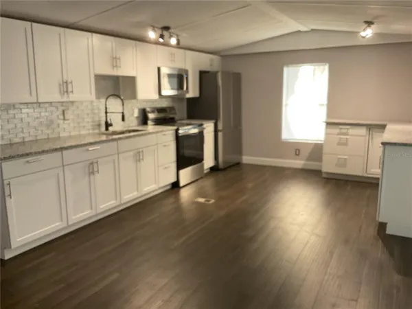 a kitchen with wooden floors and white cabinets