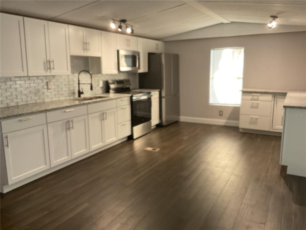 5038 Northeast Sandy Road Arcadia, FL 34266 - Photo 5 of 48 a kitchen with stainless steel appliances a sink a stove a refrigerator cabinets and a wooden floor