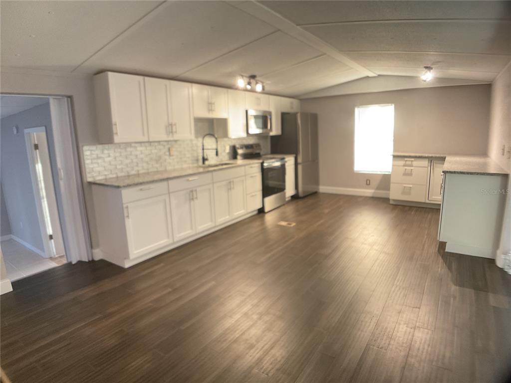 5038 Northeast Sandy Road Arcadia, FL 34266 - Photo 6 of 48 a kitchen with wooden floors and white cabinets