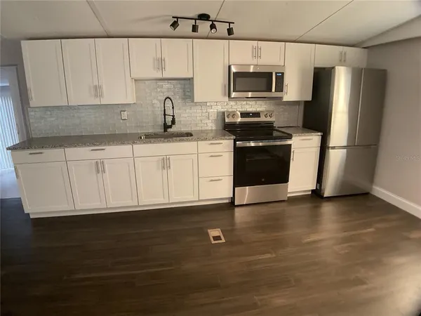 a kitchen with wooden floors white cabinets and window