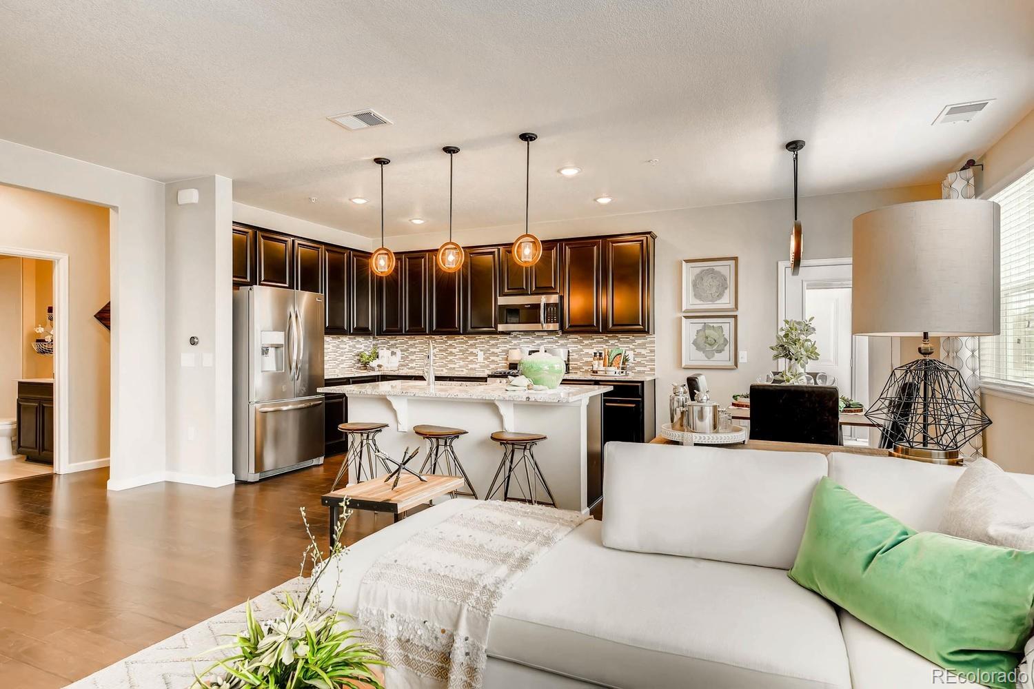 4765 Copeland Circle, Unit 103 Highlands Ranch, CO 80126 - Photo 11 of 28 a living room with furniture a fireplace kitchen view and a flat screen tv