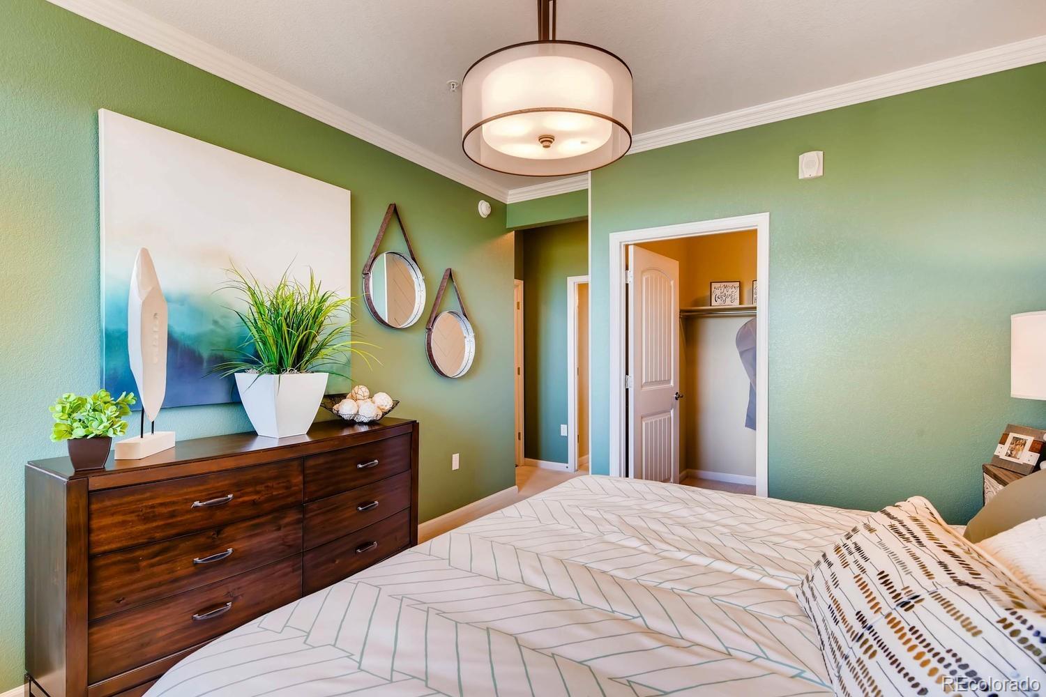 4765 Copeland Circle, Unit 103 Highlands Ranch, CO 80126 - Photo 18 of 28 a bedroom with a bed and a chandelier