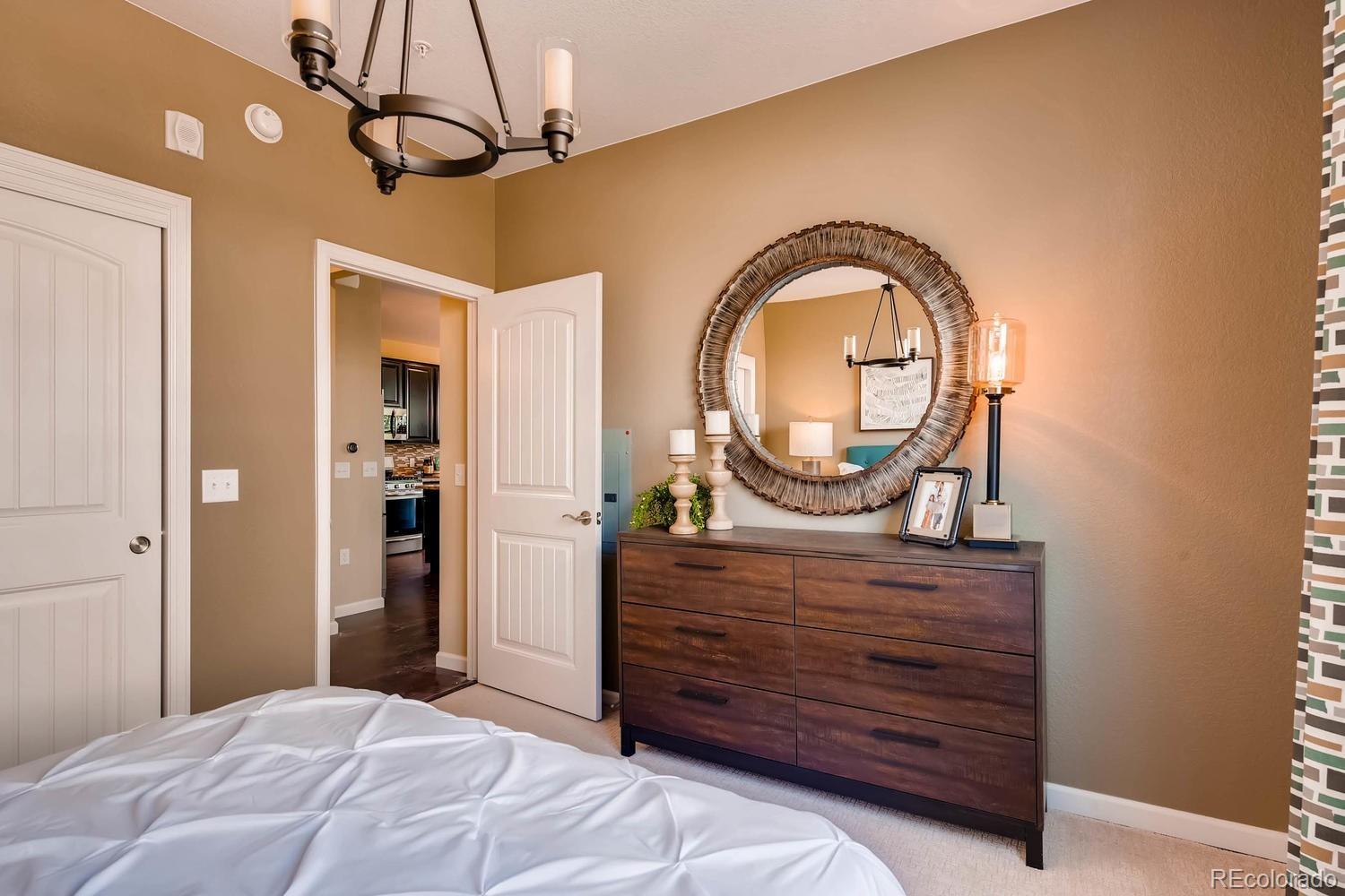 4765 Copeland Circle, Unit 103 Highlands Ranch, CO 80126 - Photo 27 of 28 a bedroom with a bed a dresser and potted plants