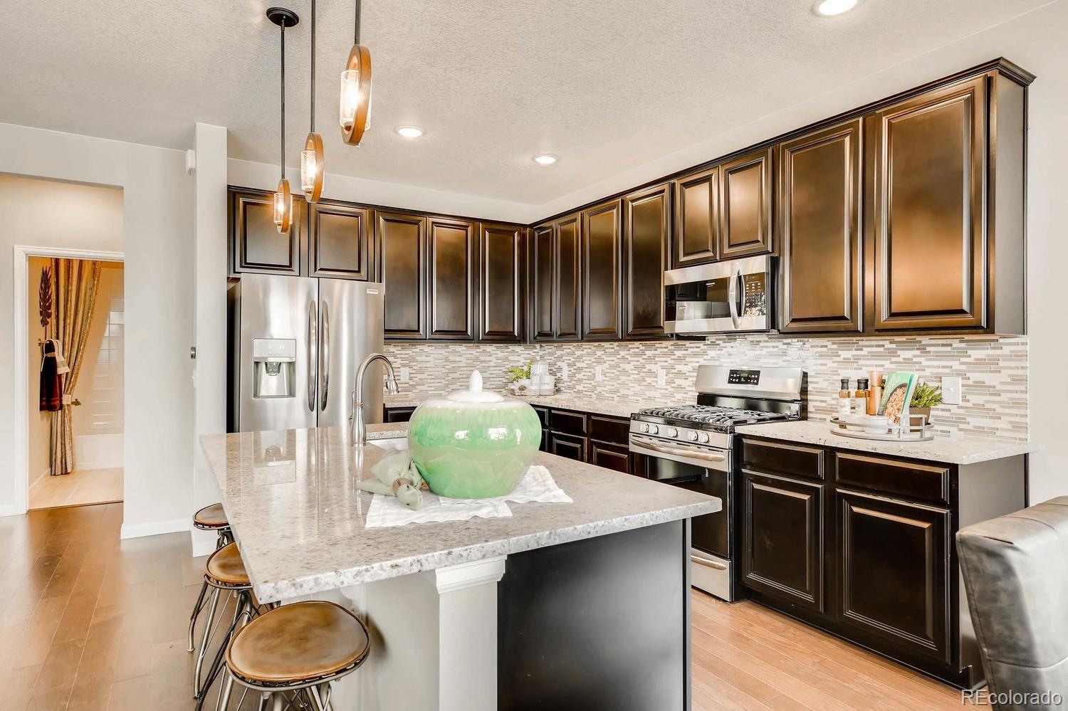 4765 Copeland Circle, Unit 103 Highlands Ranch, CO 80126 - Photo 6 of 28 a kitchen with granite countertop wooden cabinets and a stove top oven