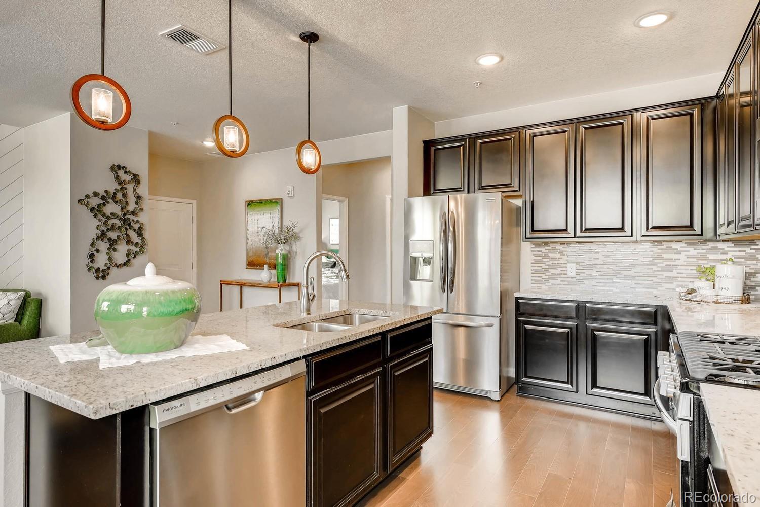 4765 Copeland Circle, Unit 103 Highlands Ranch, CO 80126 - Photo 10 of 28 a kitchen with stainless steel appliances granite countertop a sink a stove a refrigerator cabinets and chairs