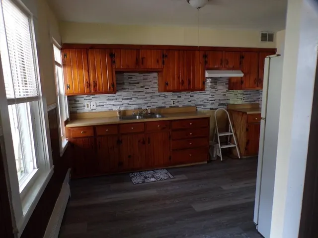 a kitchen with wooden floors wooden cabinets and a sink