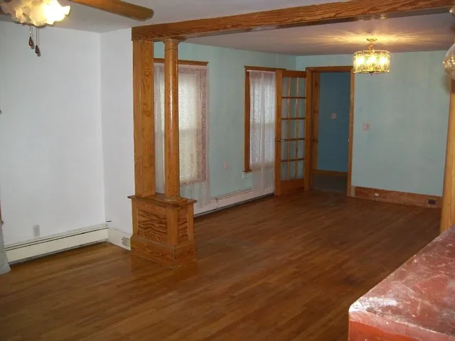an empty room with wooden floor closet and windows