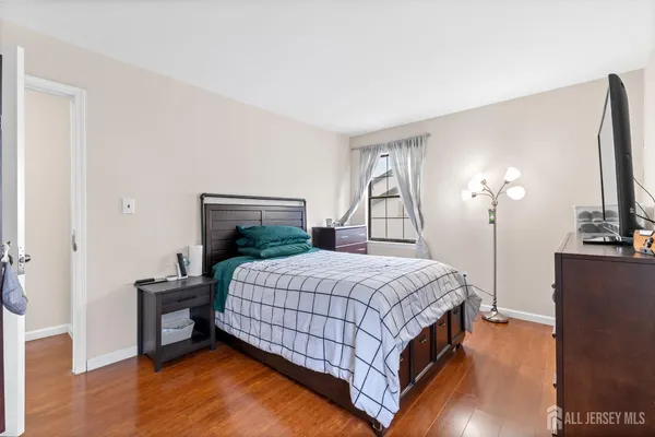 a bedroom with a bed and potted plants with the wooden floor