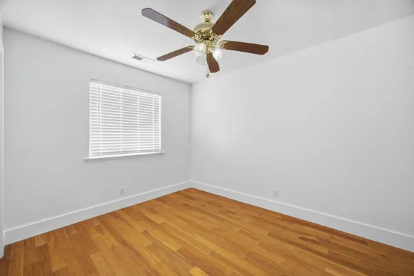 an empty room with a window and a ceiling fan