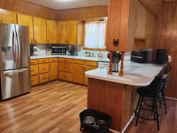 a kitchen with stainless steel appliances granite countertop a sink dishwasher a refrigerator with wooden cabinets and wooden floor