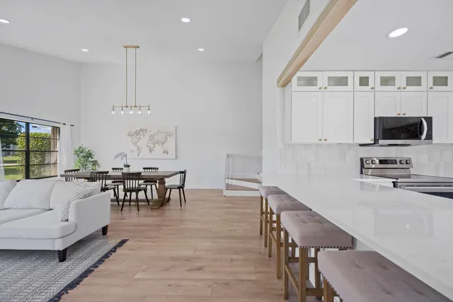 a living room with furniture a flat screen tv and kitchen view