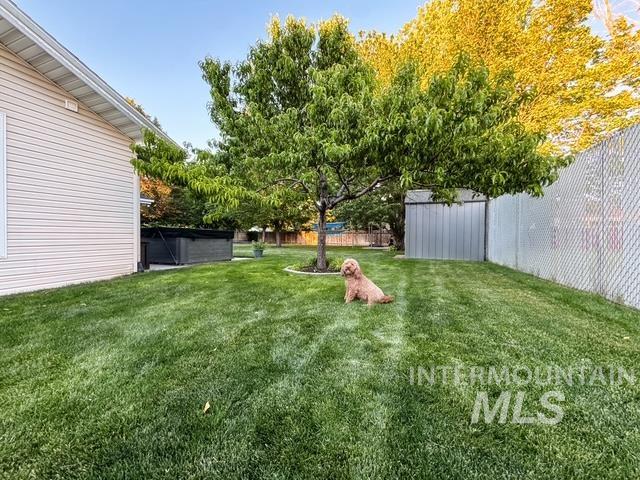 808 O'Leary Way Twin Falls, ID 83301 - Photo 34 of 37 Expansive green lawn featuring mature trees, a chain-link fence, and a storage shed