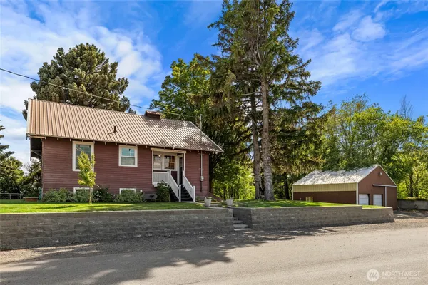 a front view of a house with a garden and trees
