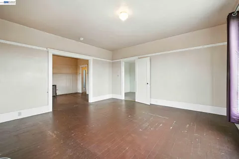 a view of an empty room with wooden floor and closet