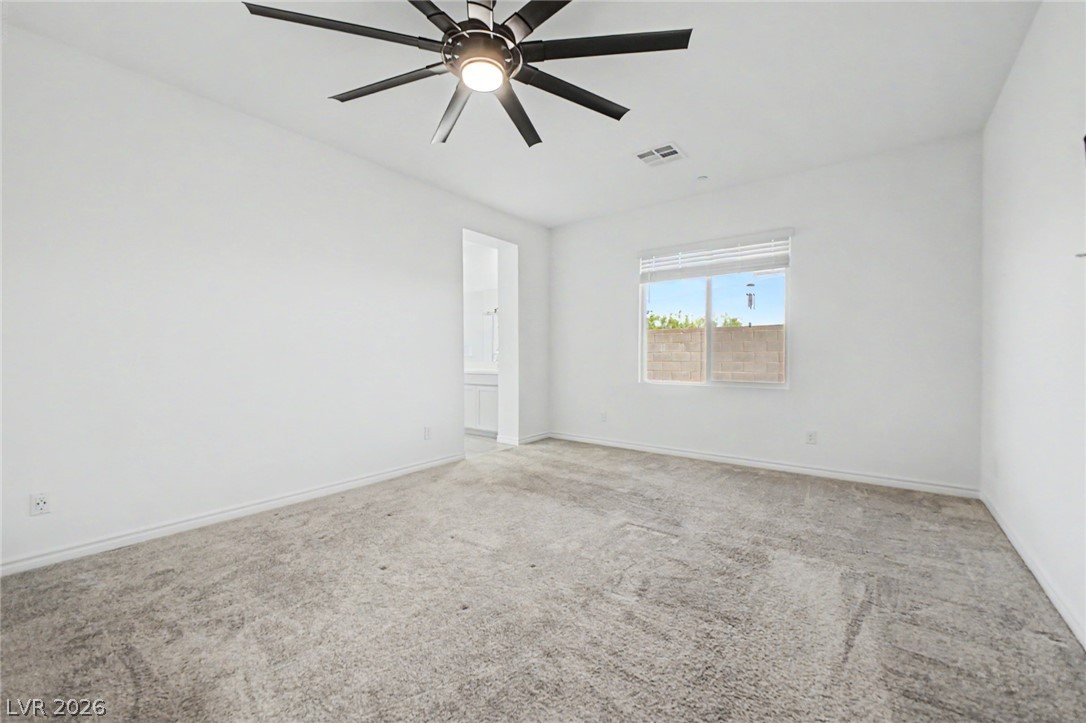 226 Augusta Ridge Henderson, NV 89015 - Photo 10 of 47 This airy bedroom features plush carpeting, a large window, and a modern ceiling fan, creating a comfortable living space.