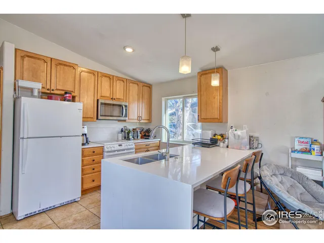 a kitchen with kitchen island a counter top space appliances a sink and a refrigerator