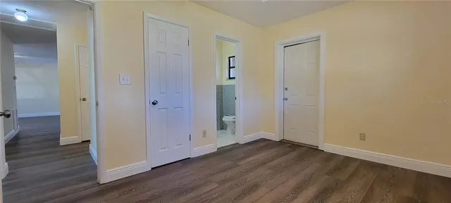 an empty room with wooden floor & closet area